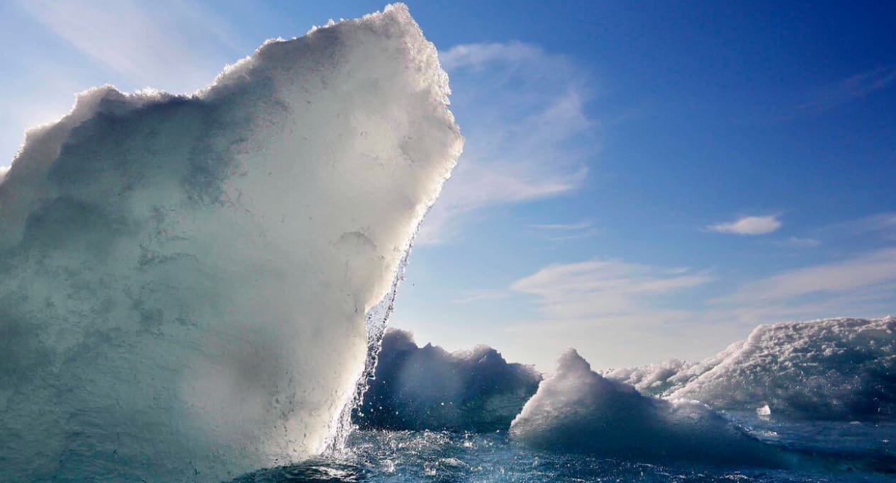 A large glacier floats amount other blocks of ice. 